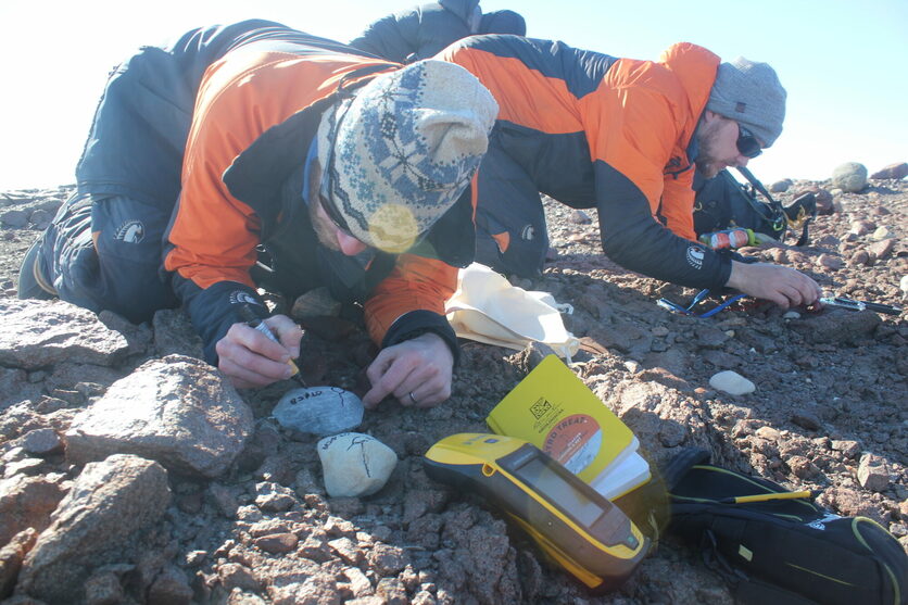 Two scientists collecting rocks in Antarctica with GPS device