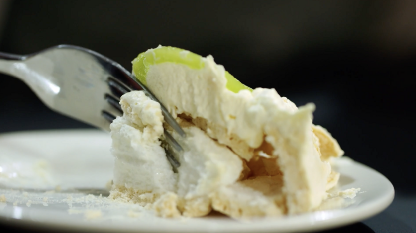 Fork slicing into serving of pavlova pudding
