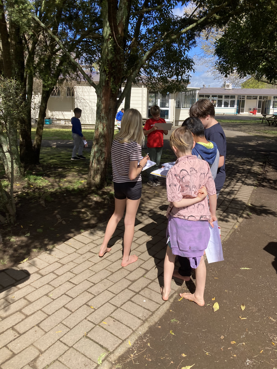 Children standing under a kōwhai tree holding sketchpads