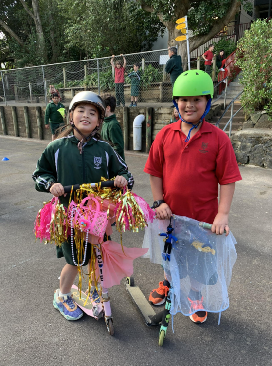 Two children with dressed up scooters in school playground.